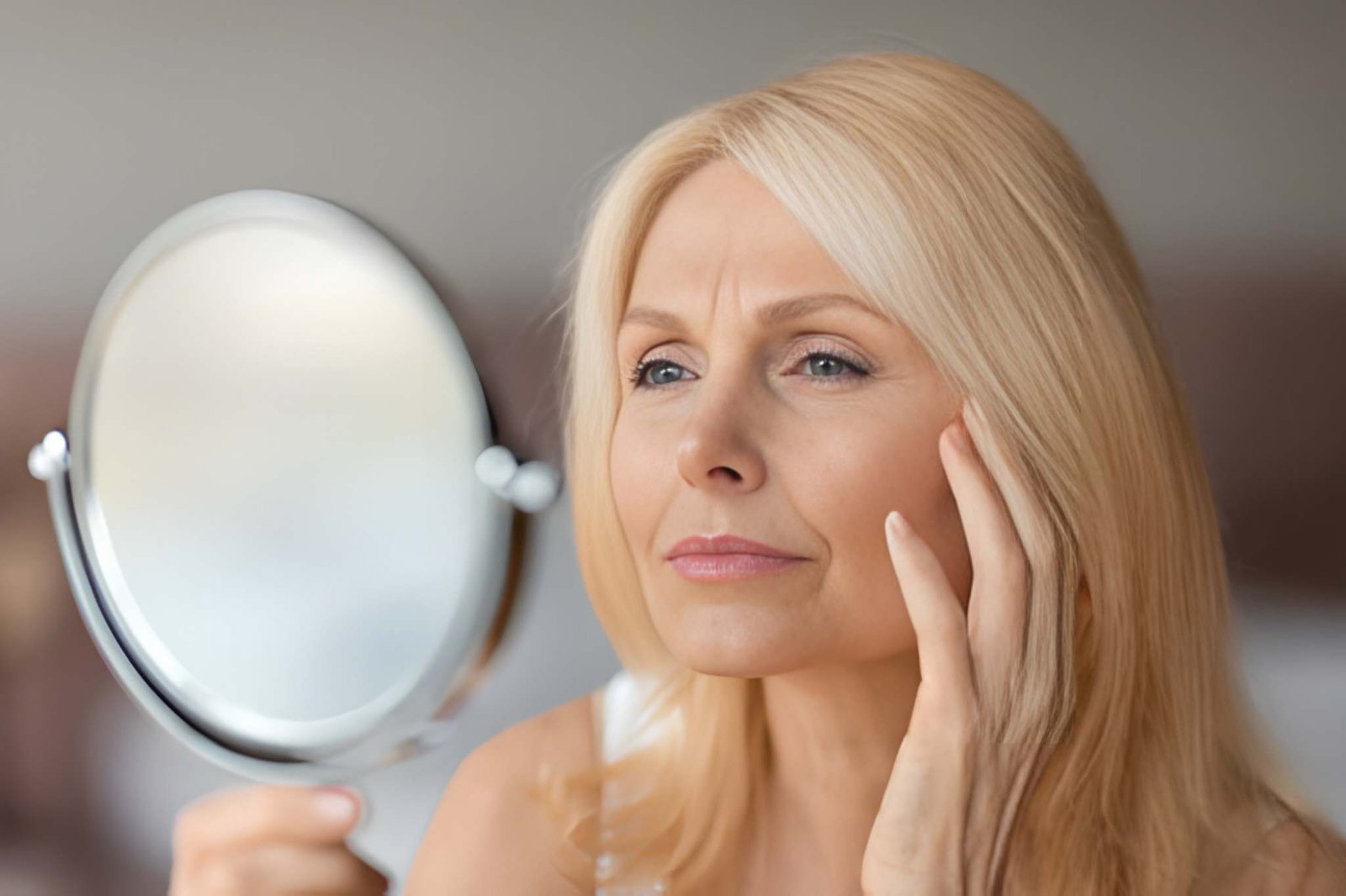 Woman examining skin in mirror